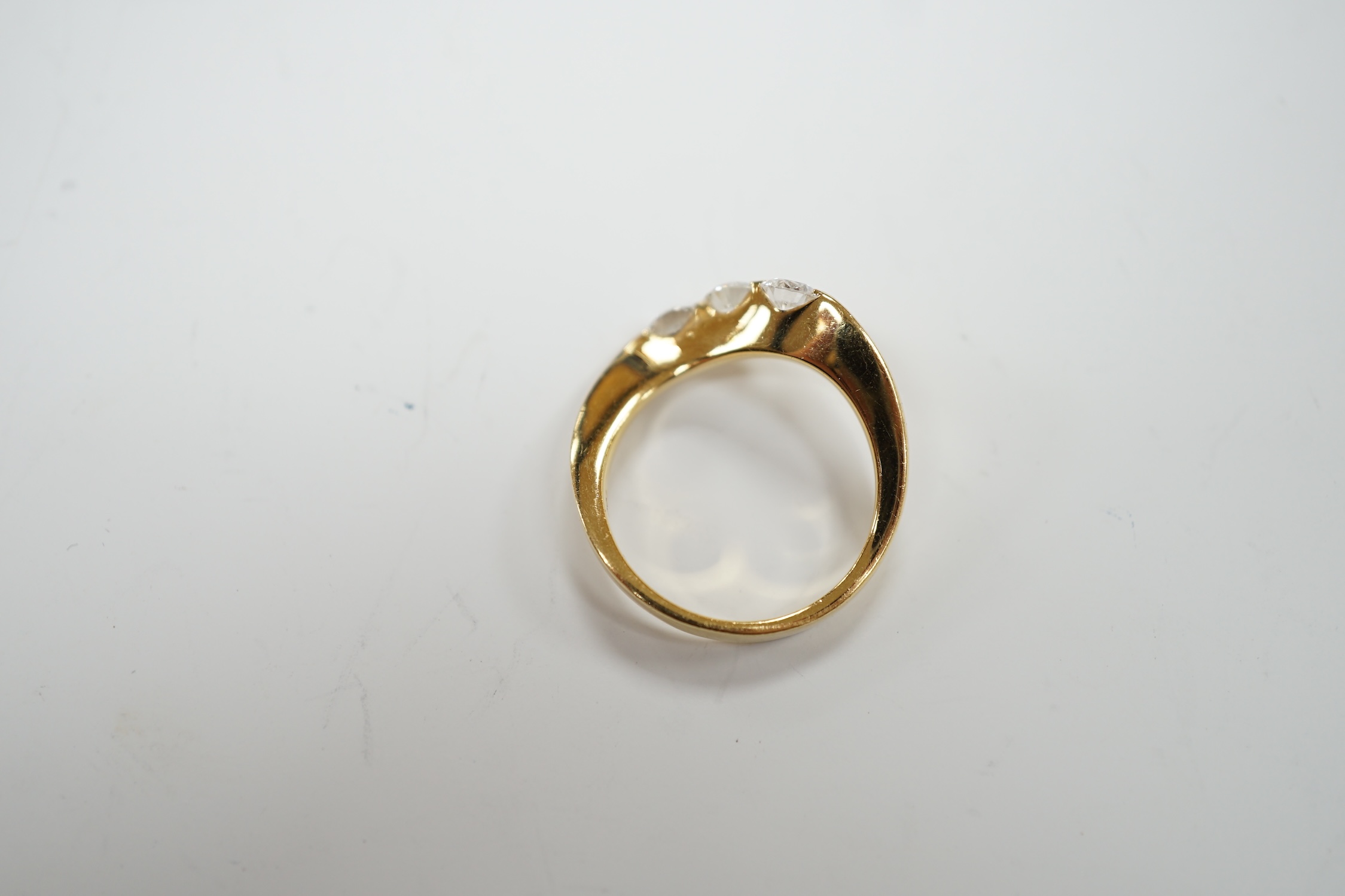 A modern 750 yellow metal and three stone diamond set crossover ring, size P, gross weight 5.4 grams.